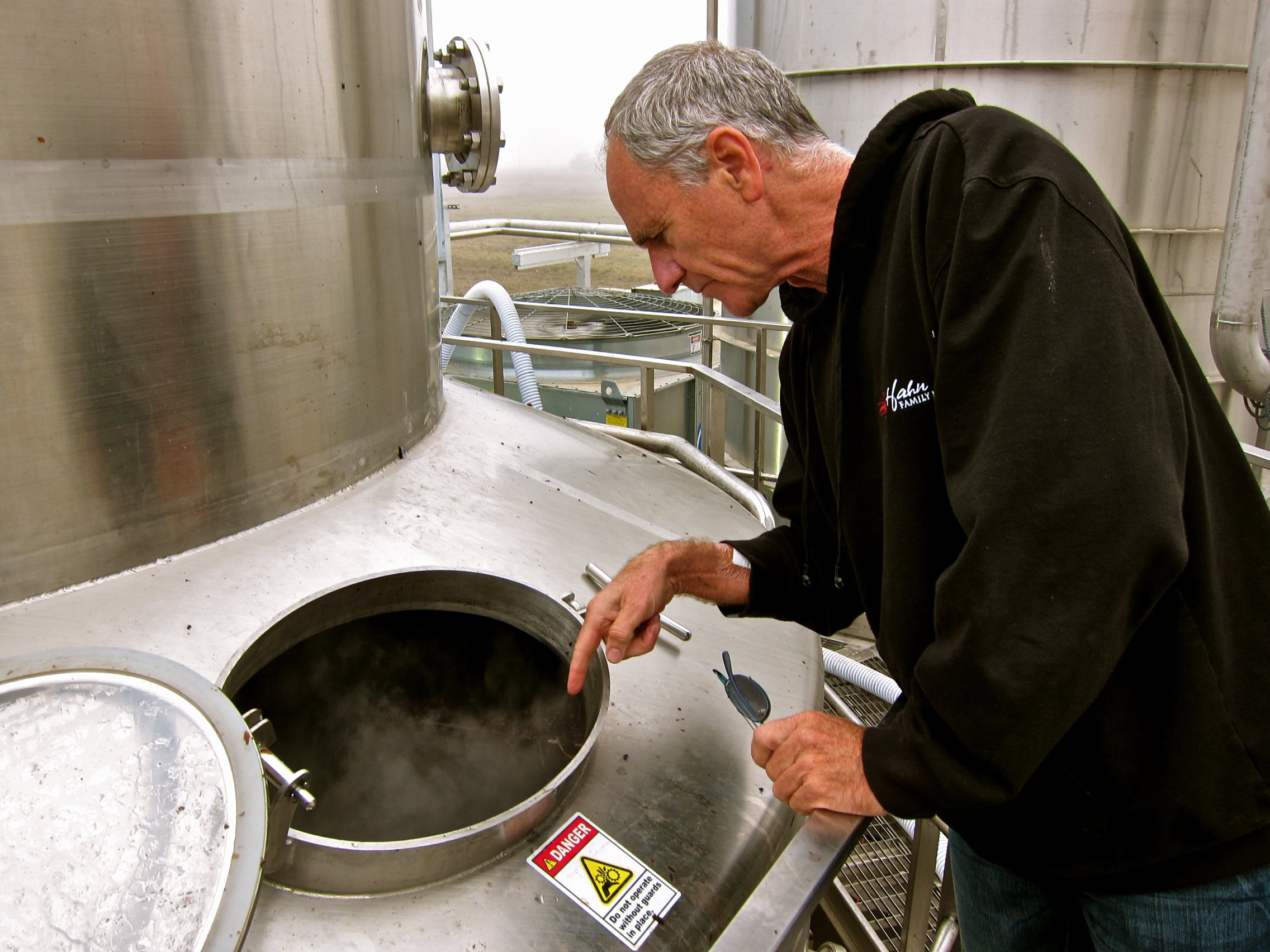 Winemaker inspecting wine fermentation tank at Lodi Winegrape Commission facility.