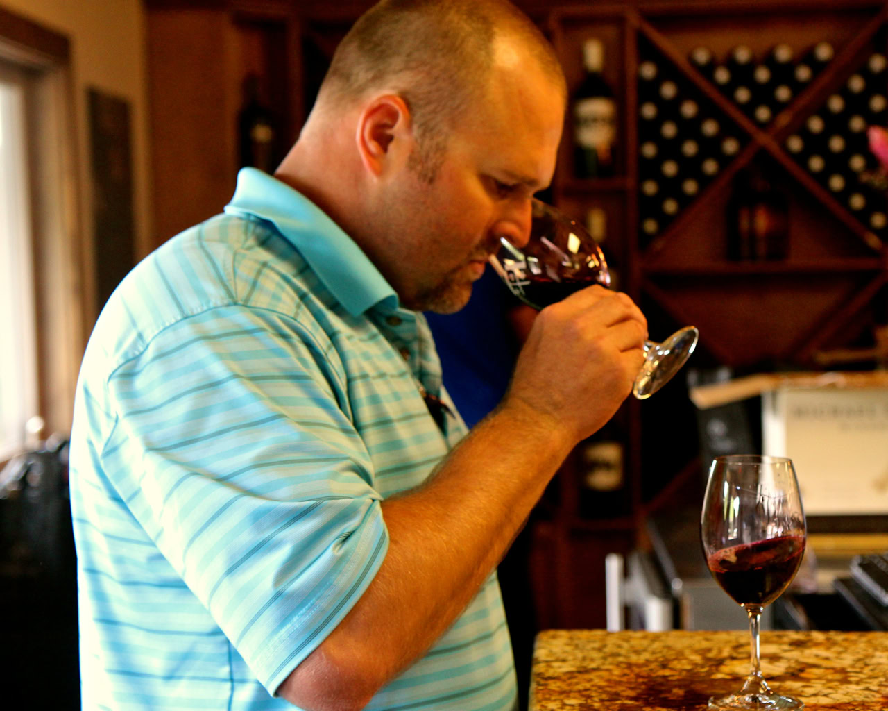 Man tasting red wine at Lodi Winegrape Commission event, showcasing local wine quality and wine culture.
