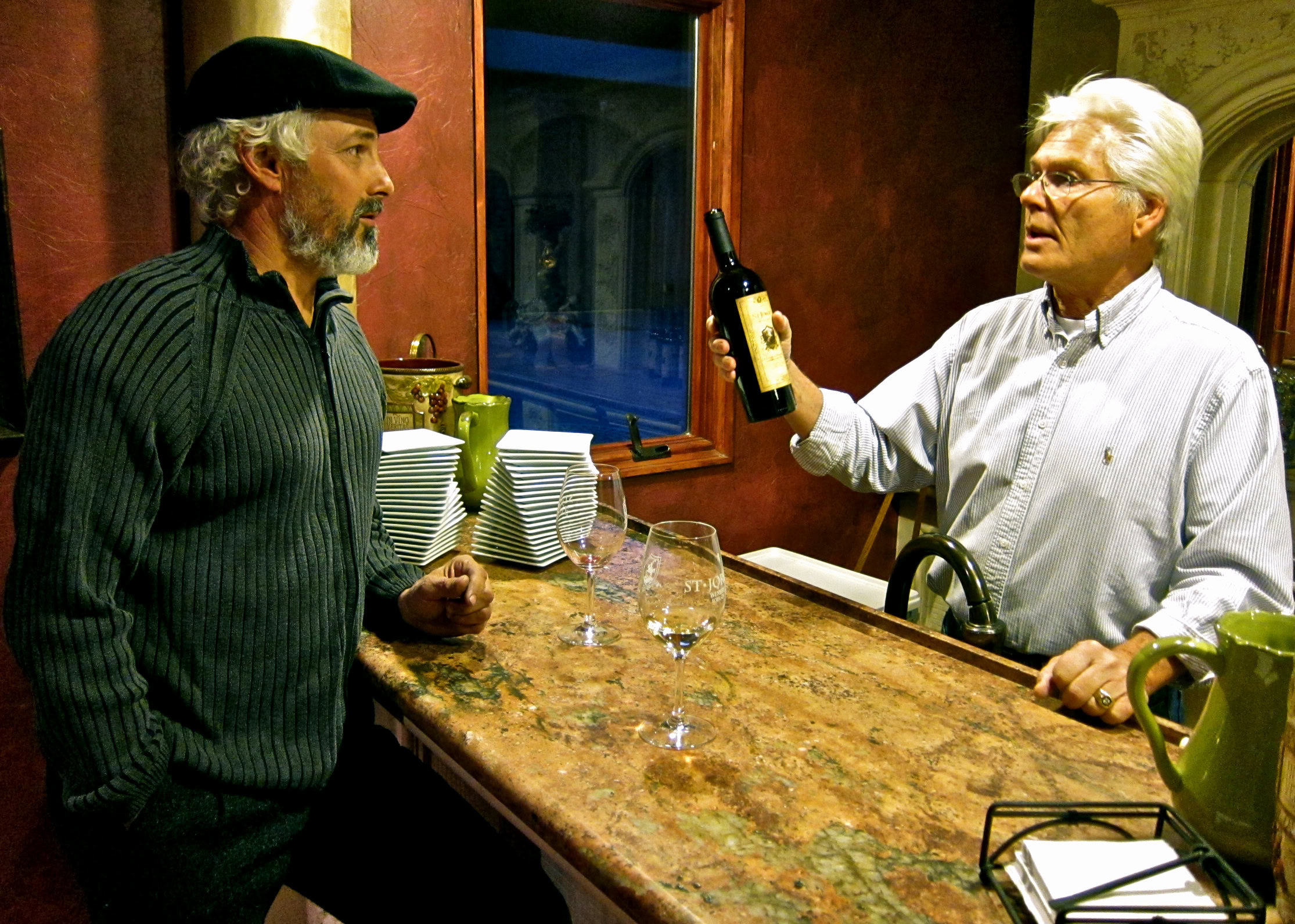 Man tasting wine at Lodi Winegrape Commission tasting room with staff member holding wine bottle.