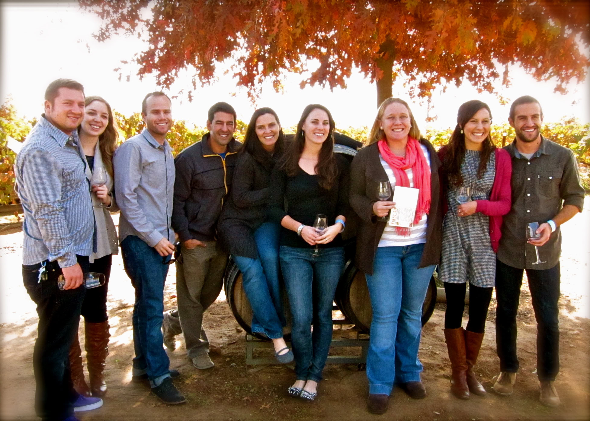 Group of people enjoying Lodi wine outdoors under autumn trees.