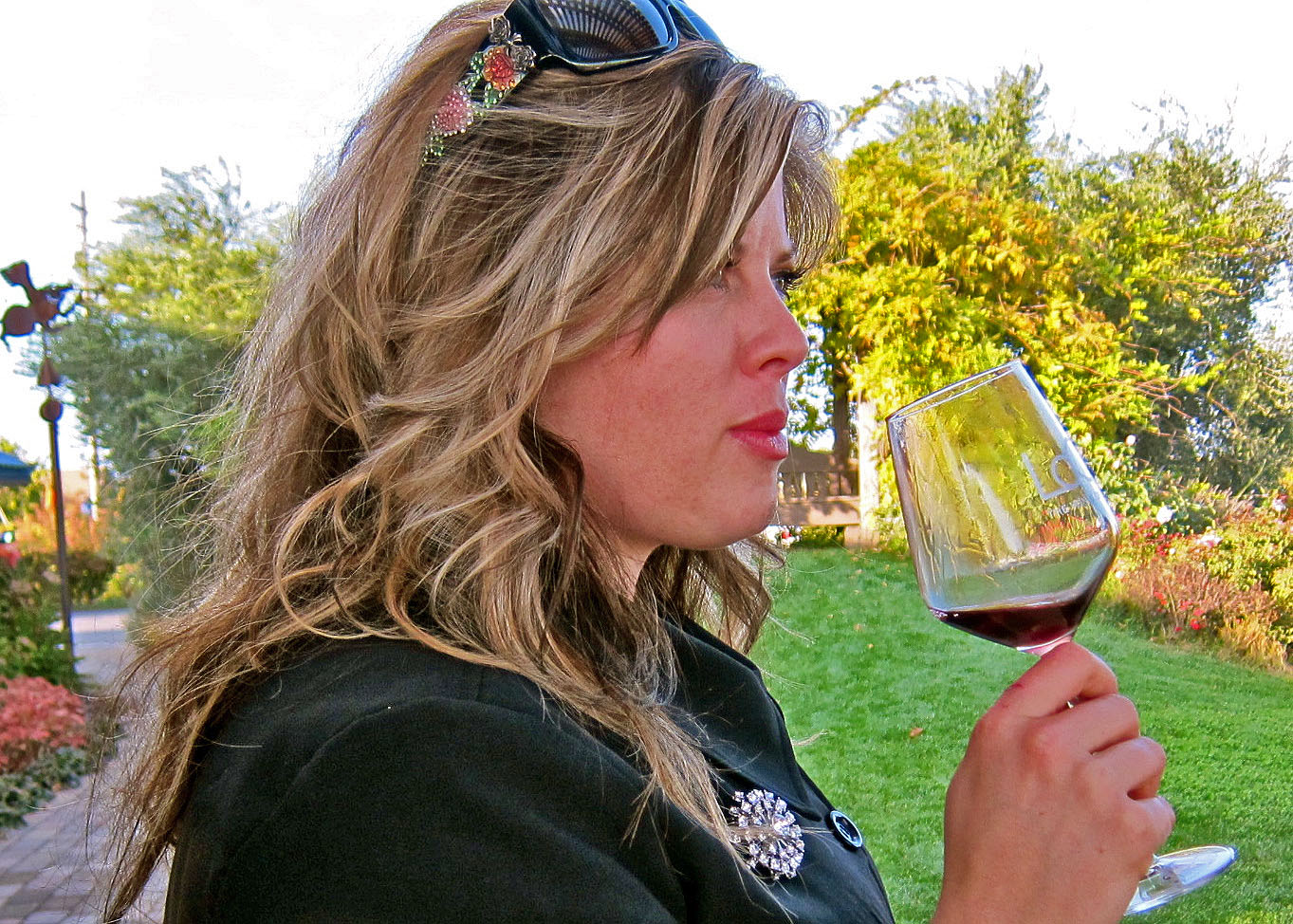 Woman tasting red wine outdoors in Lodi, California, showcasing local wine culture.