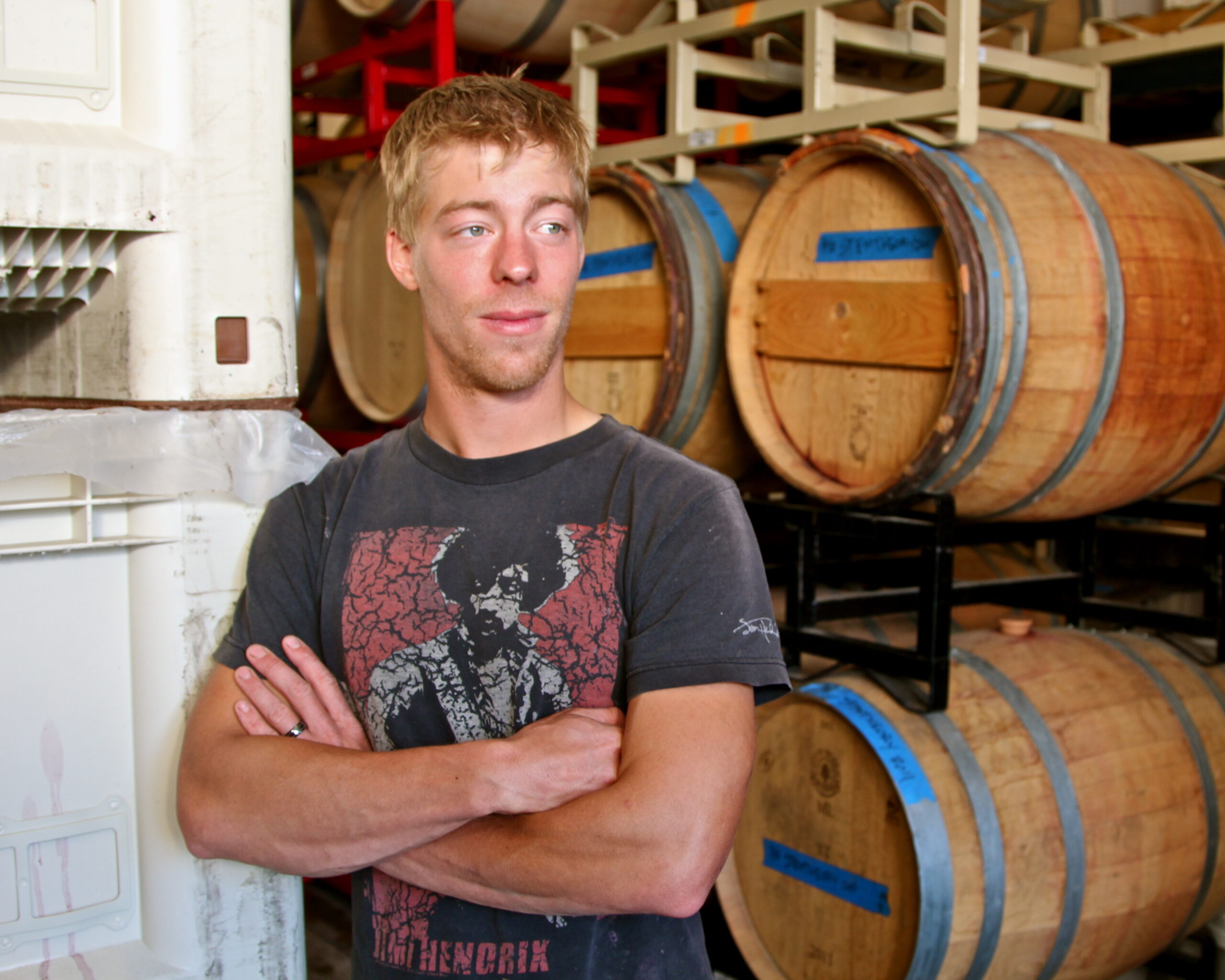 Young man in a winery with wine barrels in the background, representing Lodi Winegrape Commission.