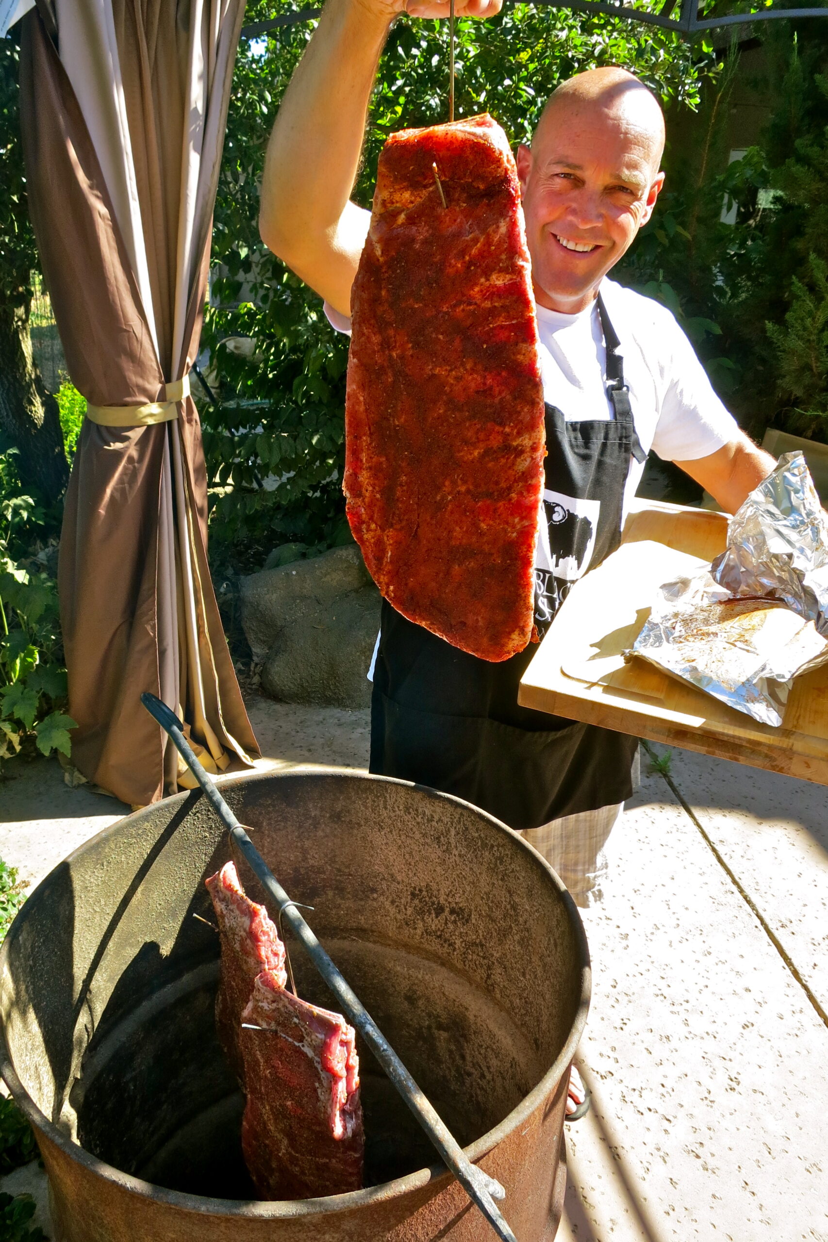 Man grilling a large piece of meat outdoors at a Lodi wine event.