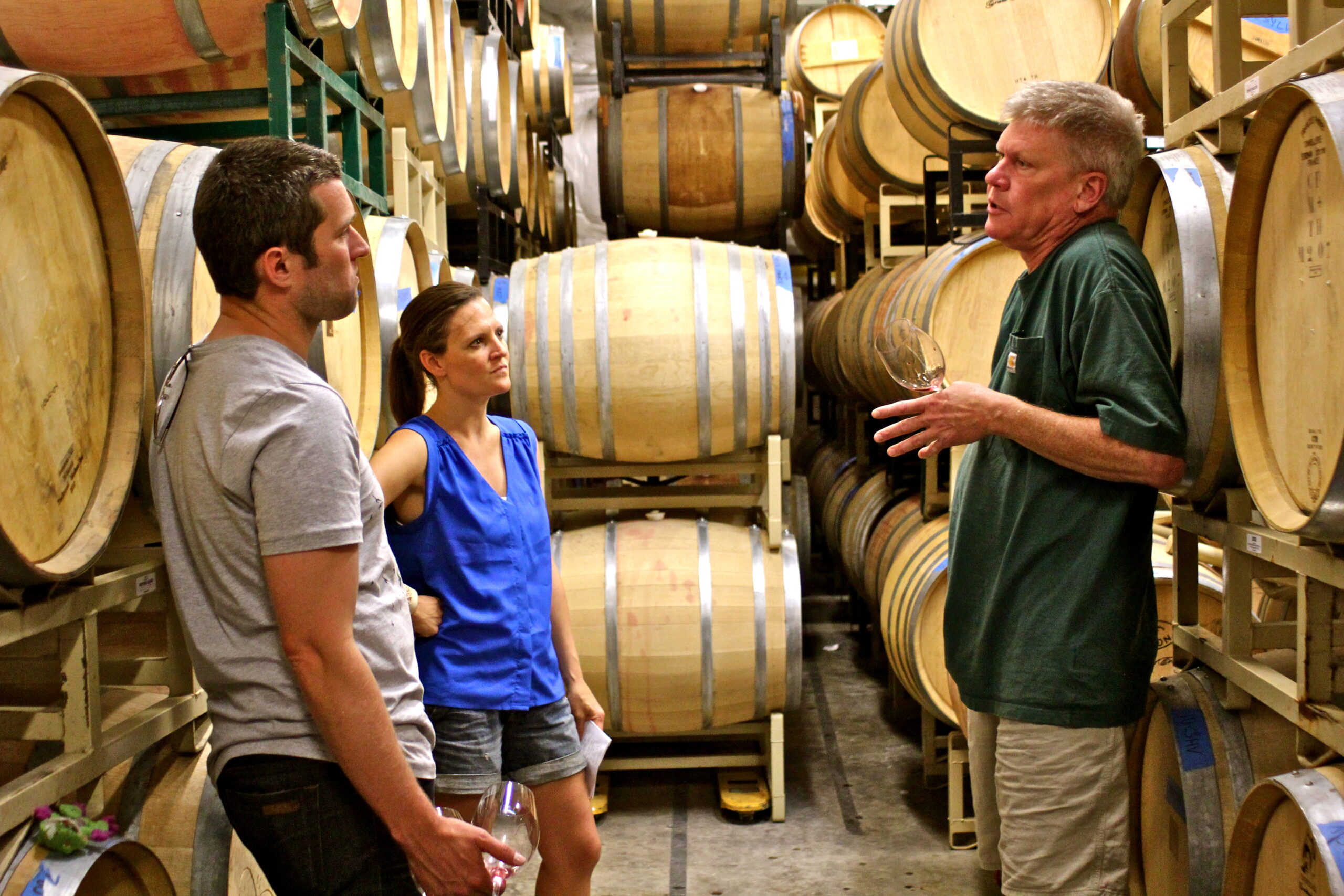 Wine industry experts discussing wine barrels at a Lodi winery with two visitors.