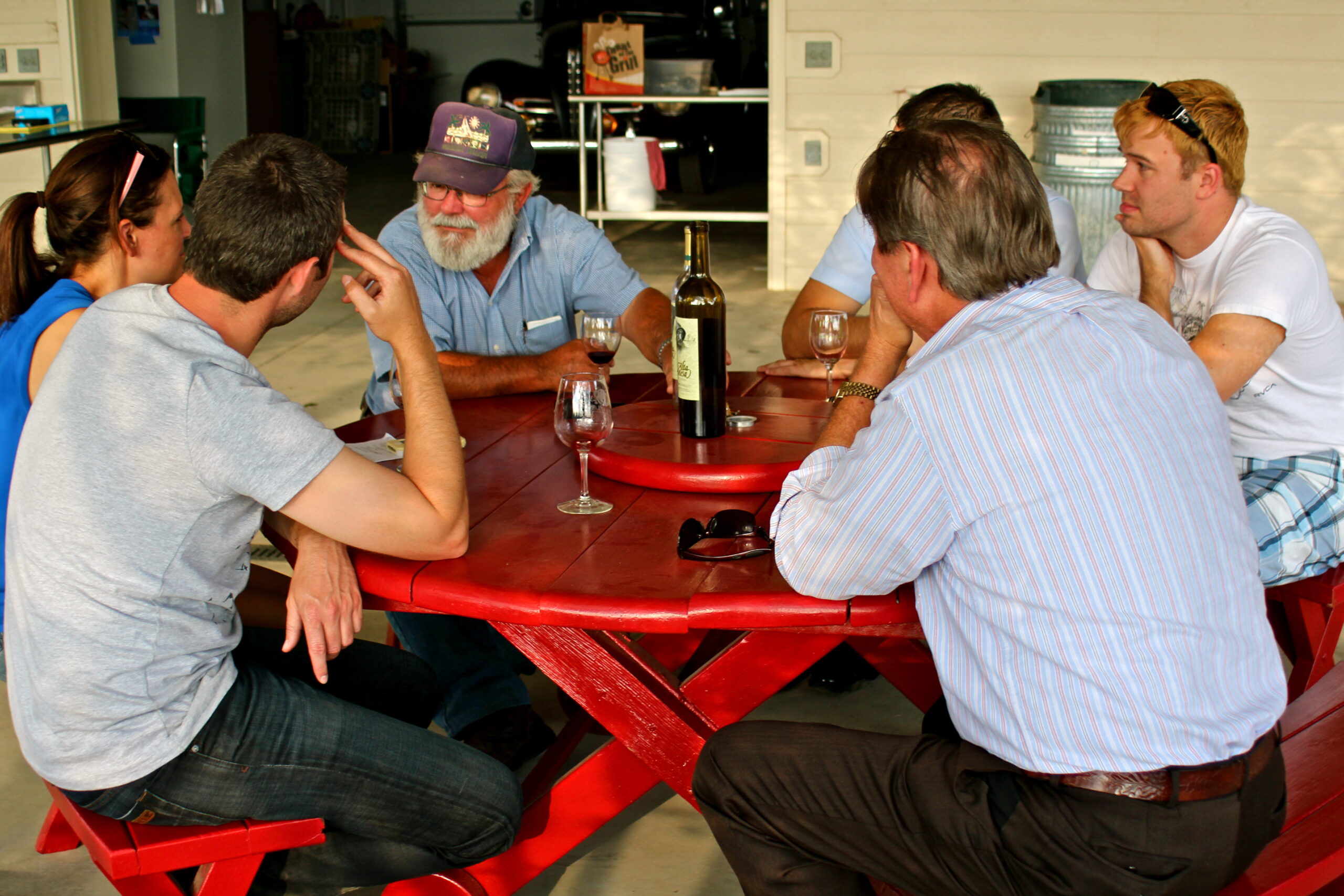 Group of people enjoying a wine tasting at a Lodi vineyard with a wine bottle on the table.