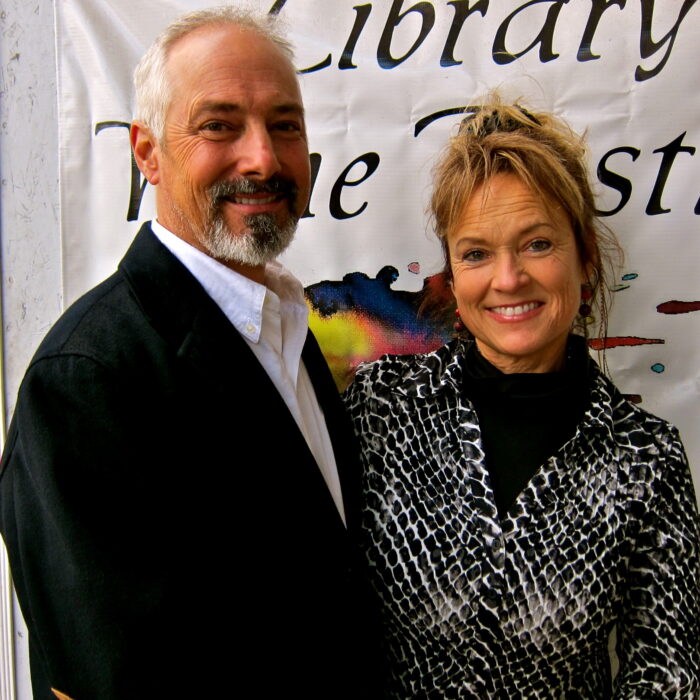 Two smiling individuals at a Lodi Winegrape Commission event, standing in front of a banner.