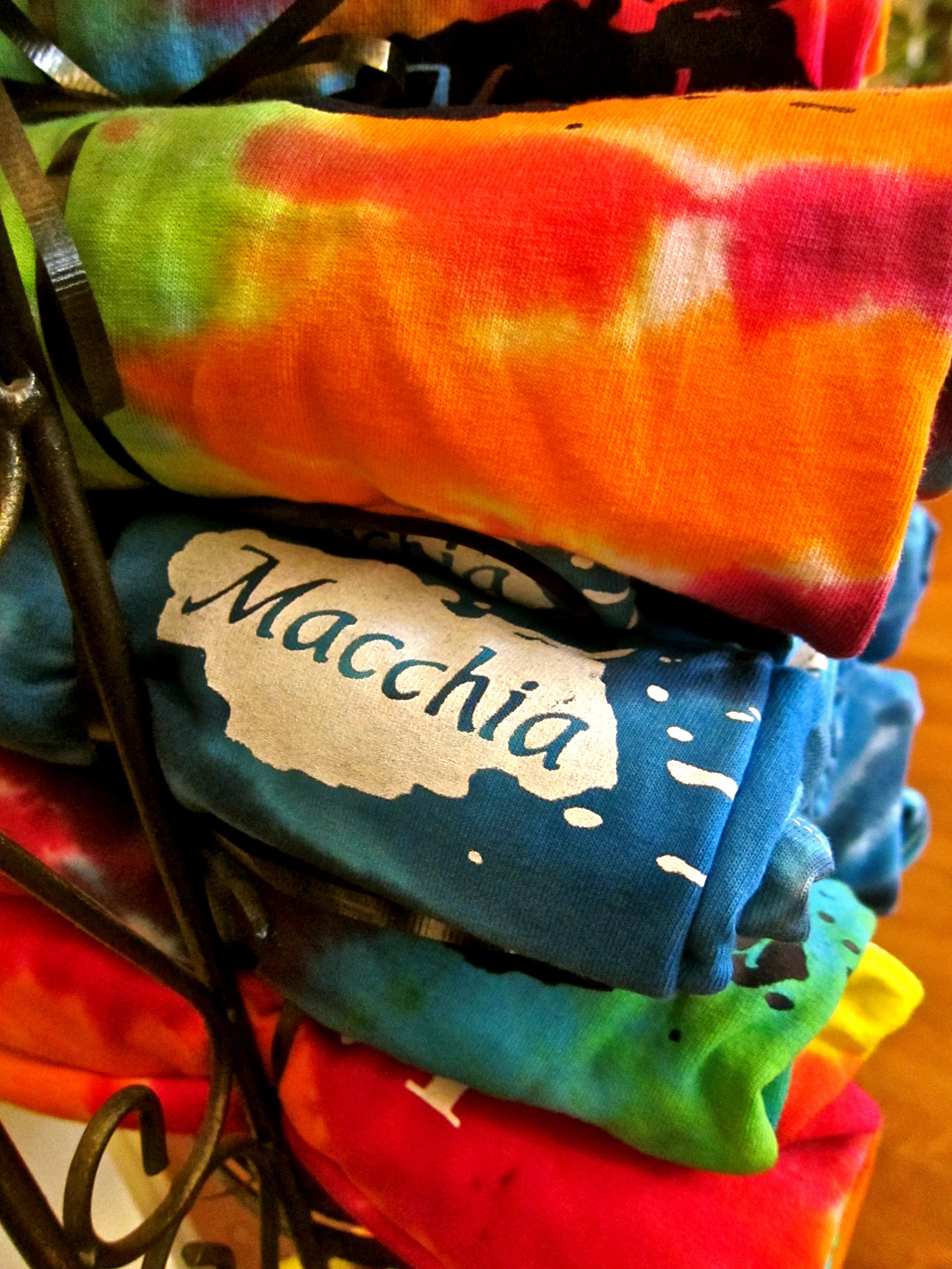 Colorful tie-dye T-shirts with Lodi Winegrape Commission and Macchia logos on display.