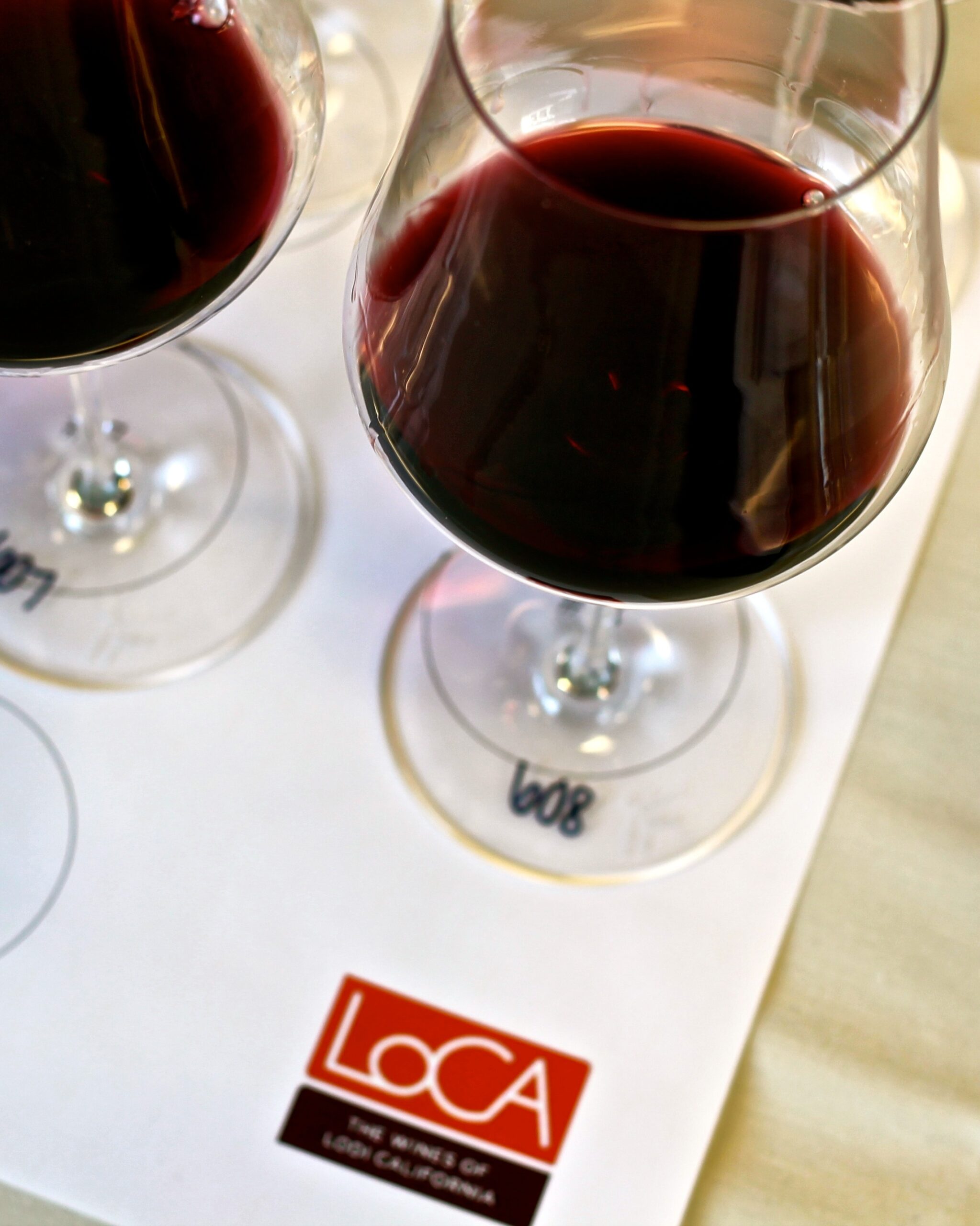 Two glasses of red wine on a tasting sheet with Lodi Winegrape Commission logo and info.