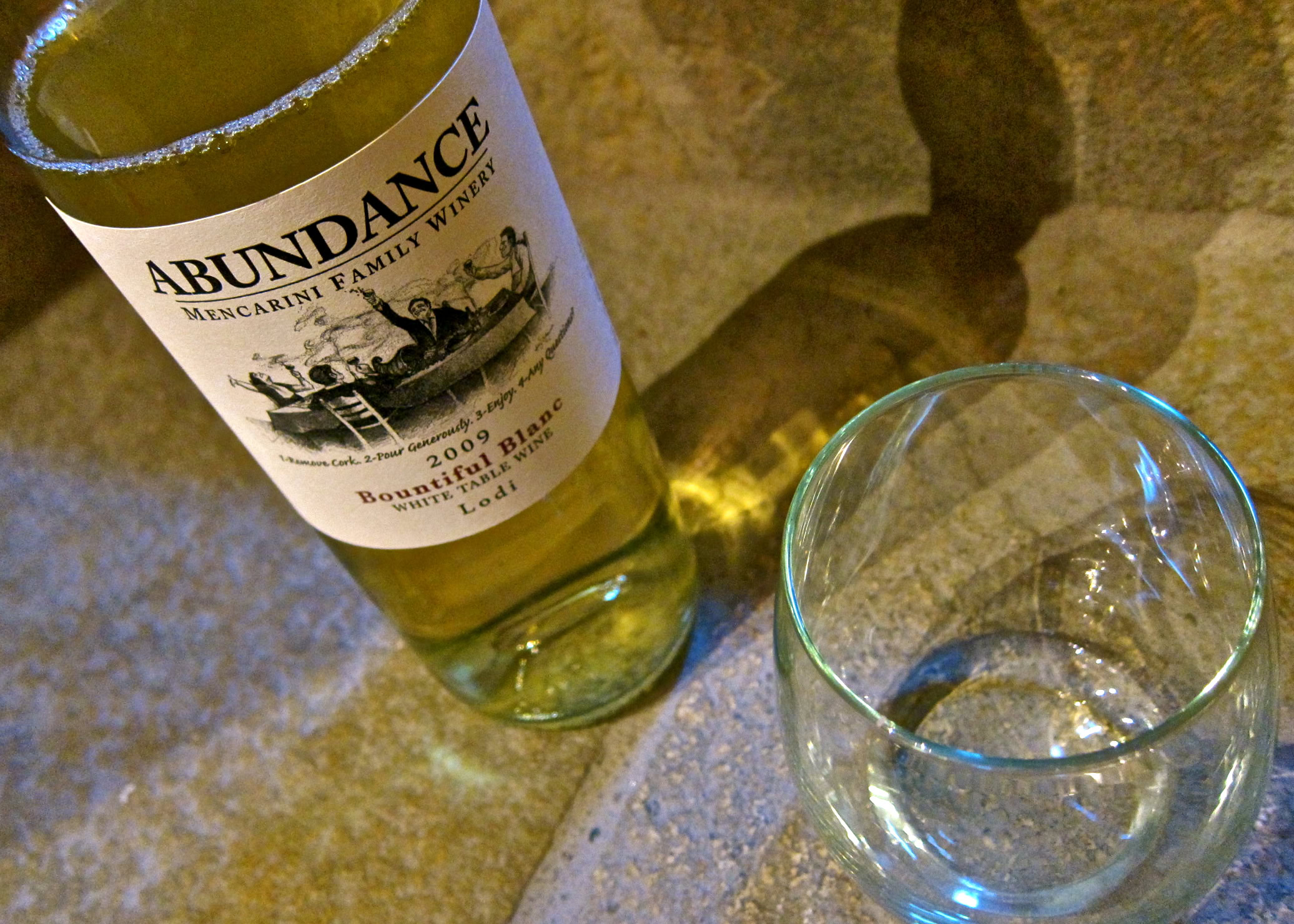 Lodi wine bottle and glass on a textured surface, showcasing local wine from Abundance Winery in Lodi.