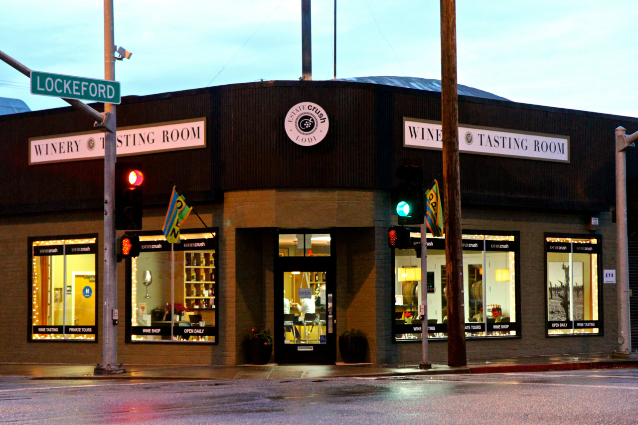 Lodi Wine Tasting Room building at the corner of Lockeford Street with traffic lights and street signs.