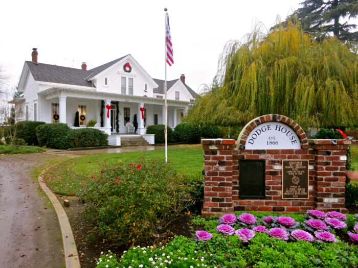 Historic Dodge House in Lodi with white exterior, American flag, and well-maintained garden.