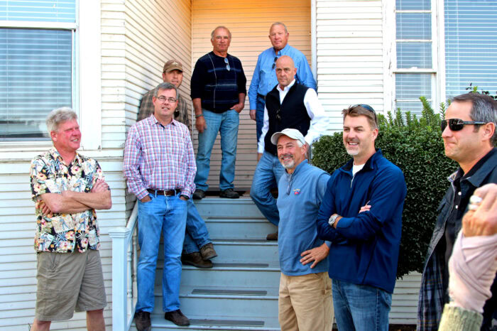 Group of men standing on steps outside a building, discussing wine grape cultivation in Lodi, California.
