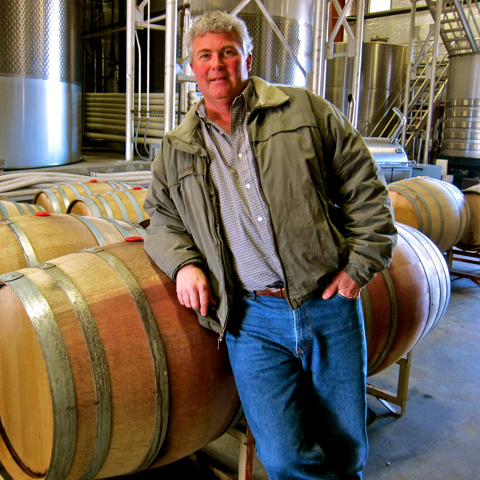 Man touring a winery with wine barrels in Lodi, California, promoting wine tourism and grape cultivation.