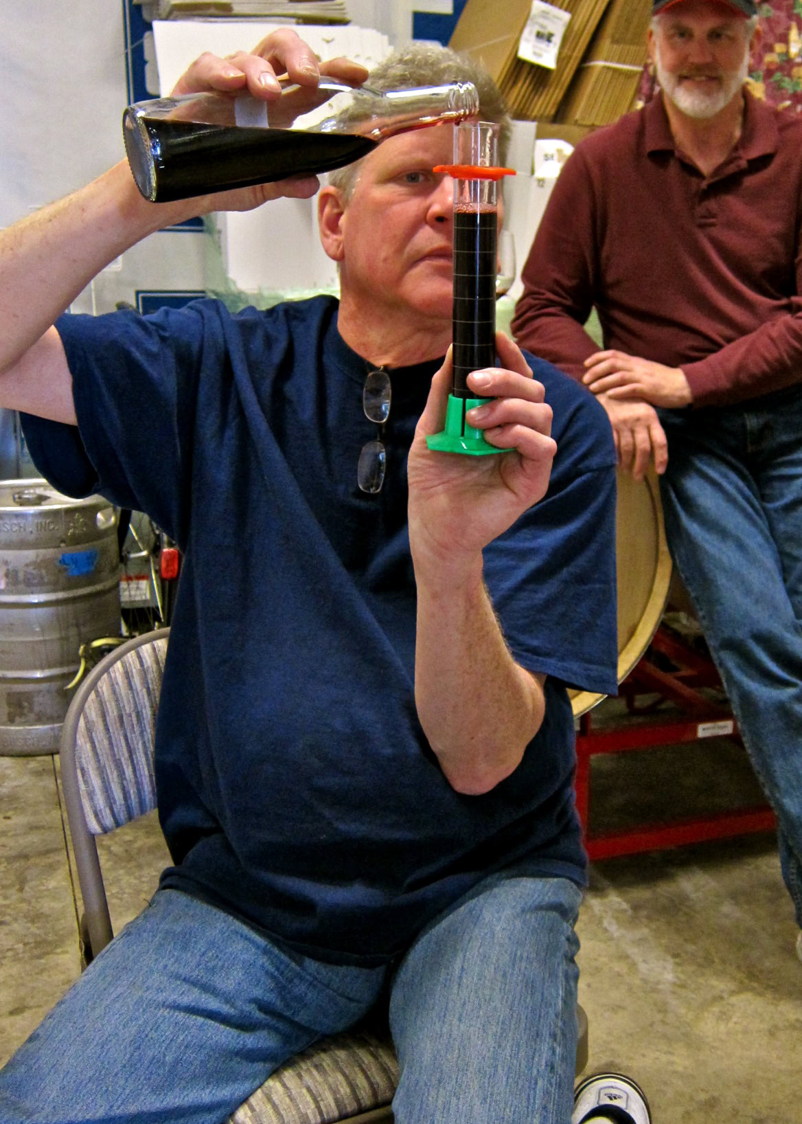 Man conducting winegrape testing with a refractometer in a winery setting.