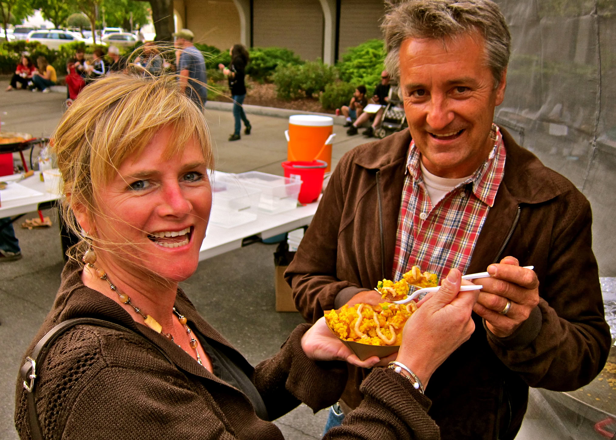 Two people enjoying food at a Lodi Winegrape Commission event, smiling and sharing a plate outdoors.