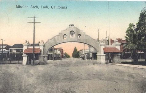 Historic Mission Arch in Iodi, California, with vintage buildings and street scene.