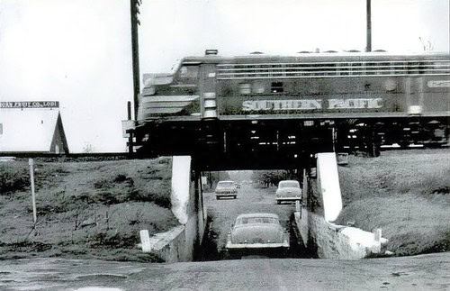Black and white photo of a train crossing over a highway underpass in Lodi, California.