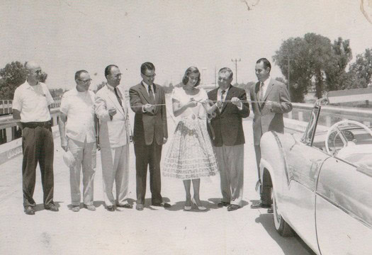 Historical black-and-white photo of officials and a woman at a ribbon-cutting ceremony for Lodi Winegrape Commission.