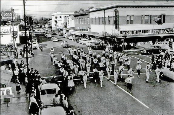 Black and white photo of a busy downtown street in Lodi with people, cars, and buildings from the early 20th century.
