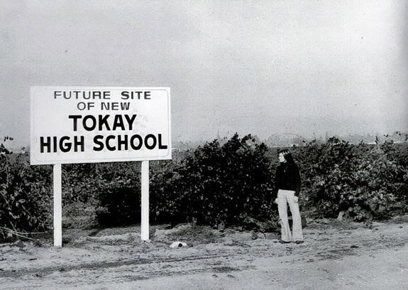 Black and white photo of a man looking at a sign for future Tokay High School site.