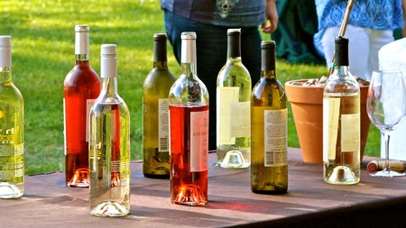Selection of various wine bottles from Lodi Winegrape Commission on a table outdoors.
