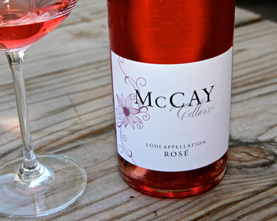 Lodi Rosé wine bottle from McCay Cellars with a glass of rosé wine on a wooden table.