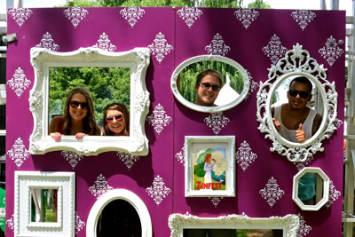 Two women and two men posing with decorative frames on a purple wall at a Lodi Winegrape Commission event.