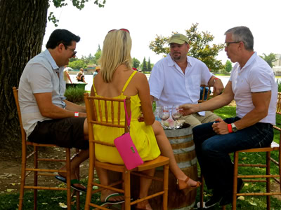 Group of four people enjoying wine tasting outdoors at Lodi Winegrape Commission event.