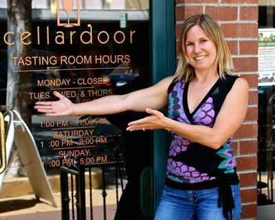 Smiling woman welcoming visitors at Lodi Winegrape Commission tasting room entrance.