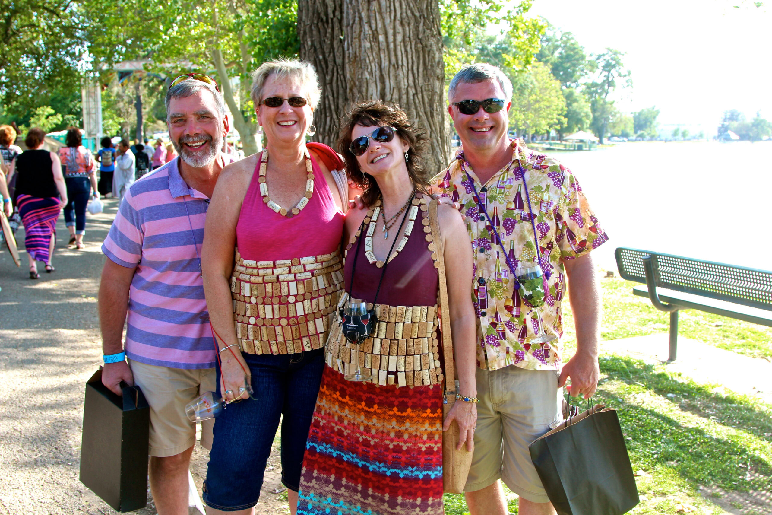Group of four smiling adults at Lodi Winegrape Commission event outdoors in a park.