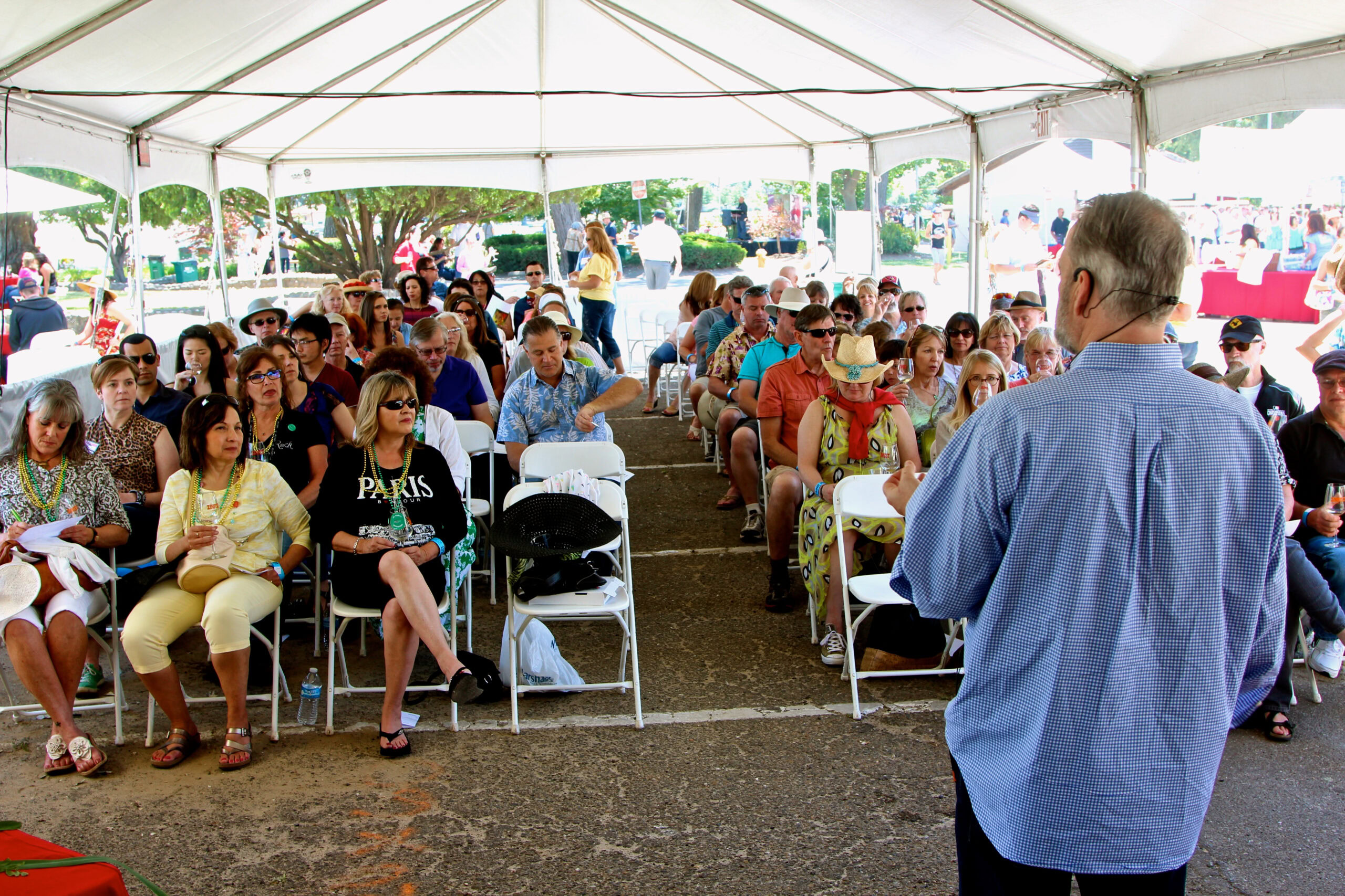 Audience attending a presentation at the Lodi Winegrape Commission event under a large white tent.