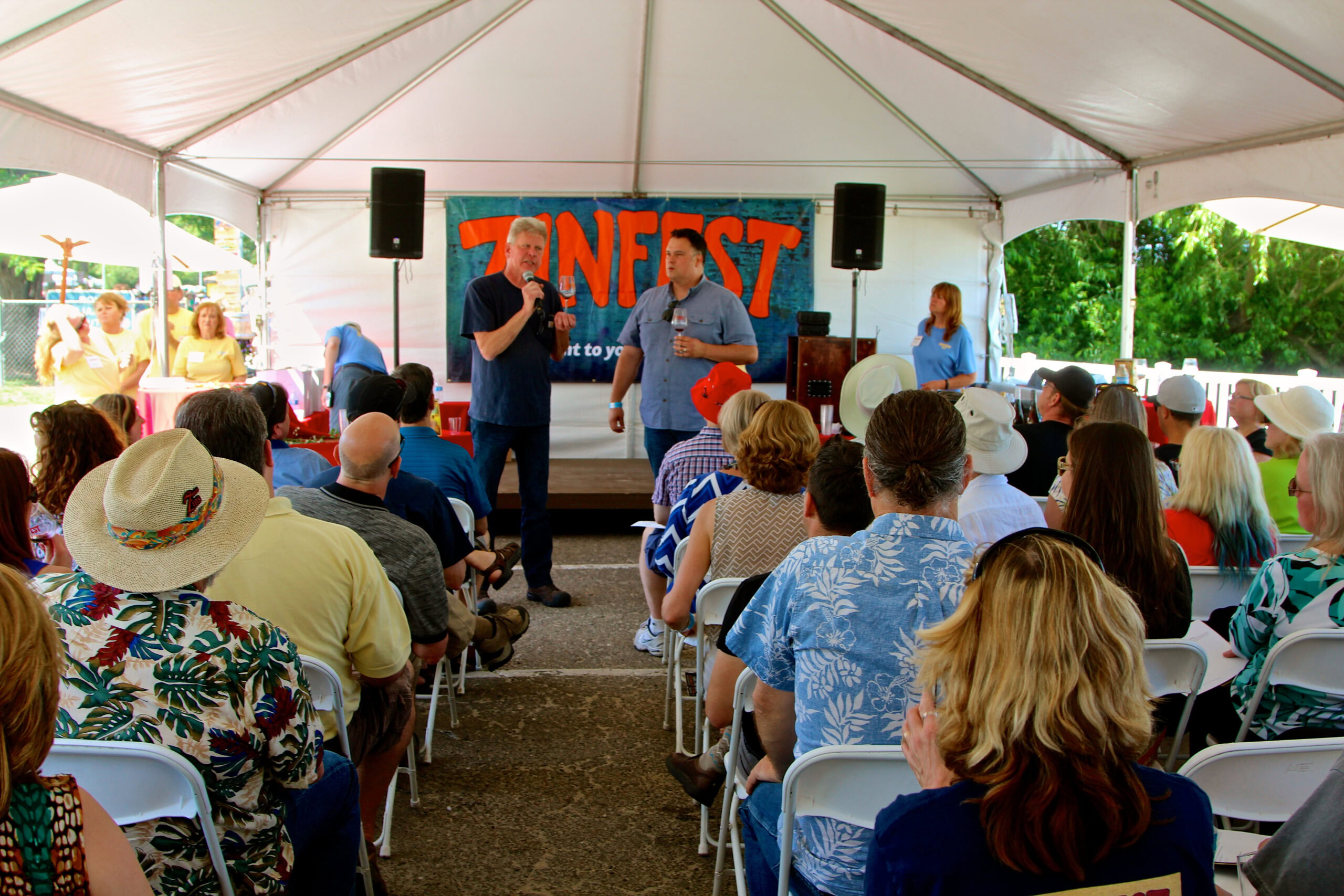 People attending a Lodi Winegrape Commission event under a tent with speakers and a banner reading 'INFERSTY'.