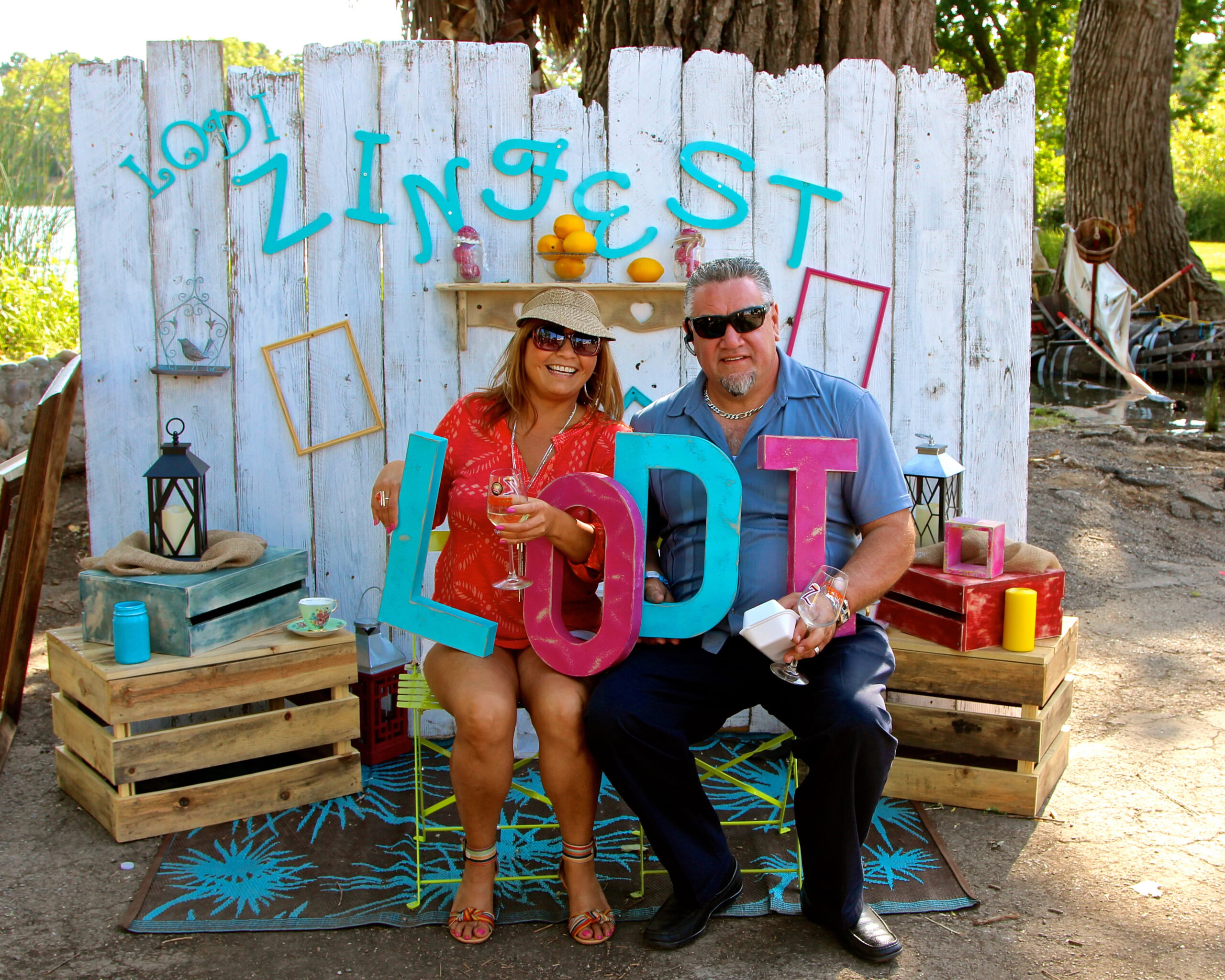Two people at Lodi Winegrape Commission event with colorful decorations and wine glasses.