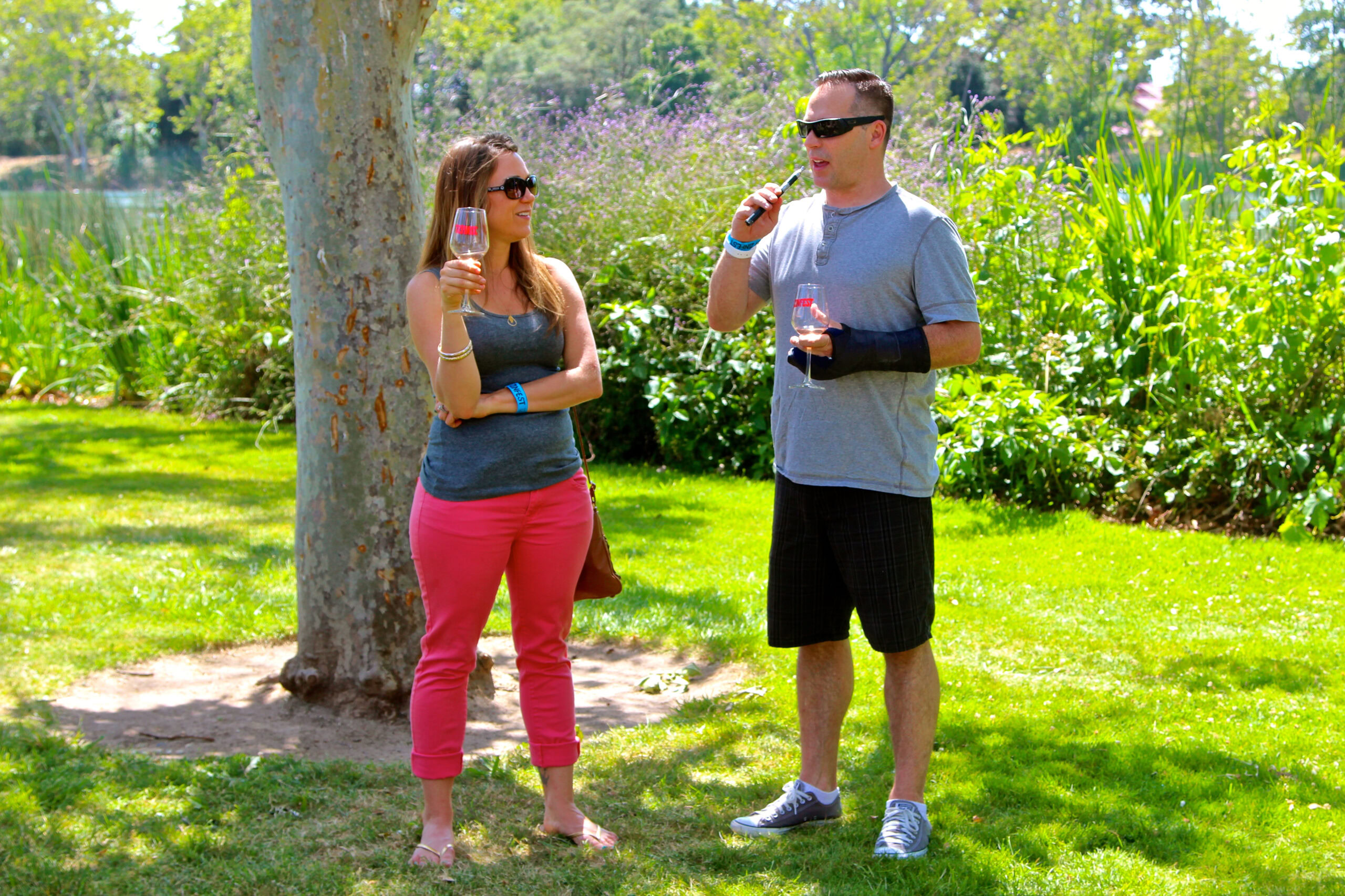 Two people drinking wine outdoors in a lush vineyard setting in Lodi, California.