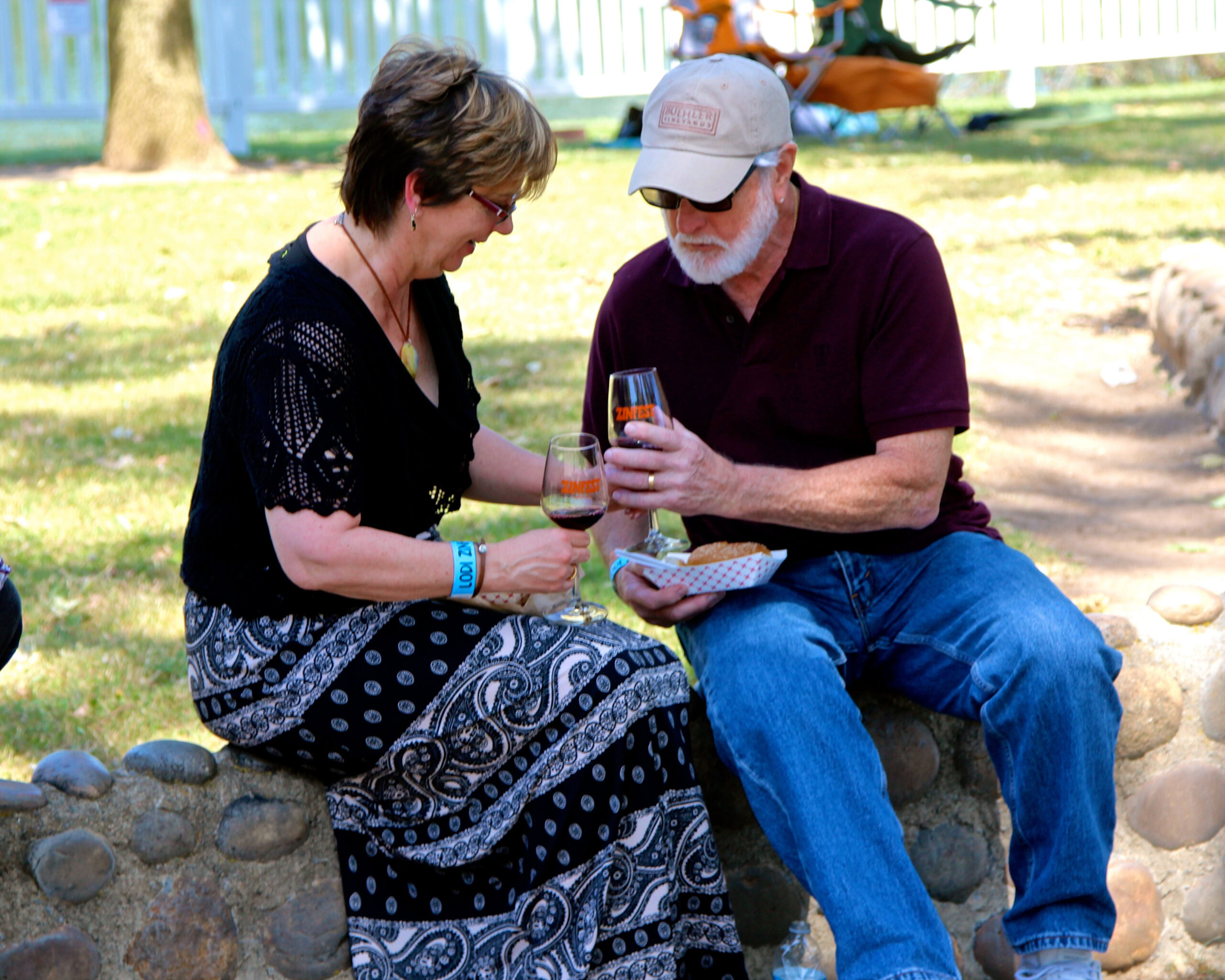 Two people enjoying wine tasting outdoors at a Lodi Winegrape Commission event.