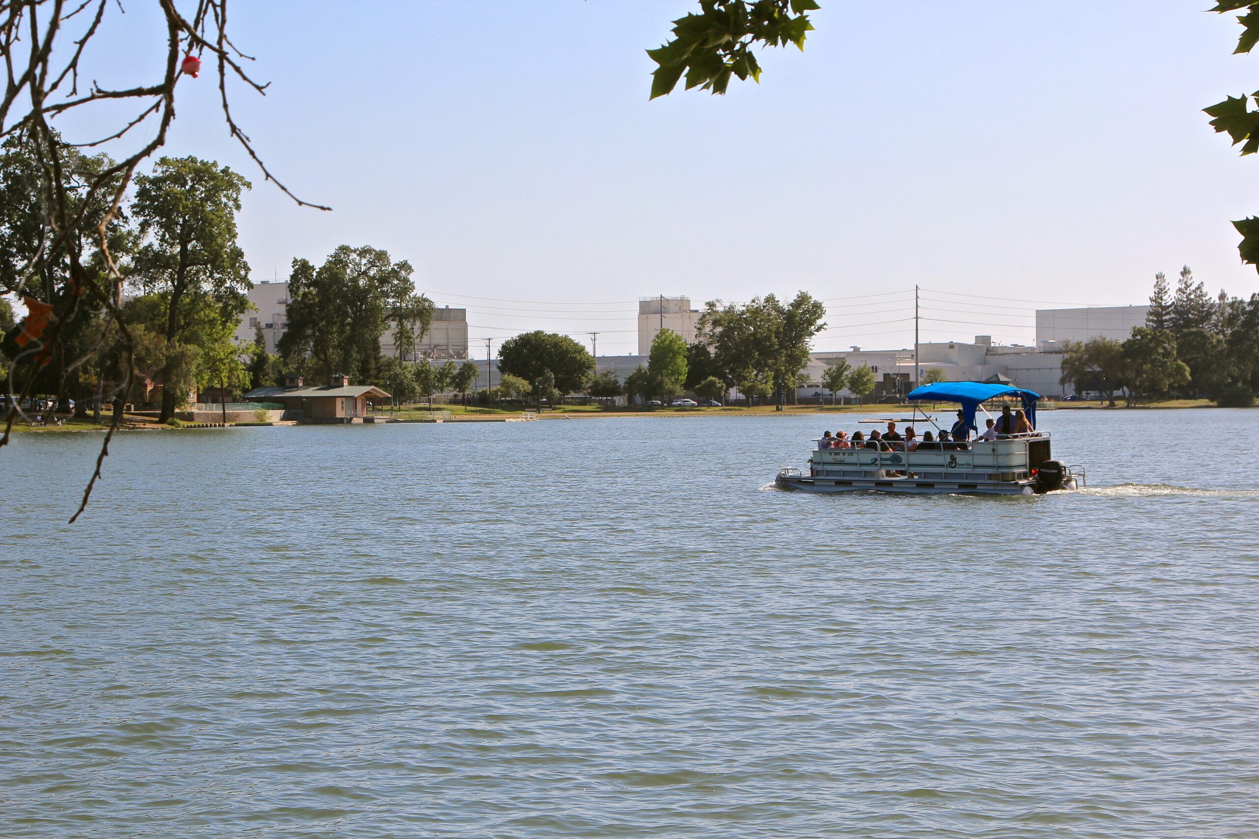 People enjoying a boat ride on a lake with trees and buildings in the background, promoting Lodi wine region.