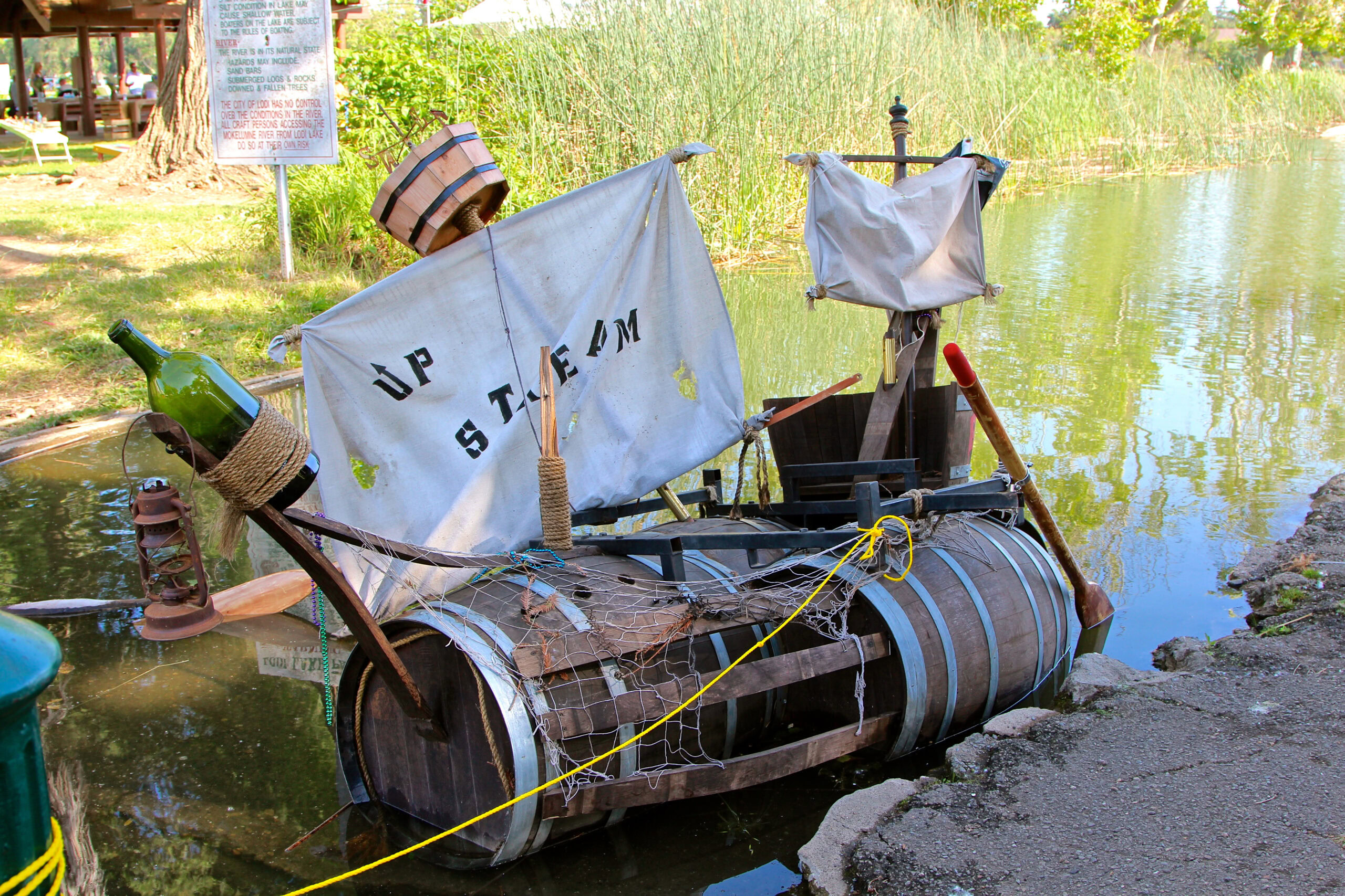 Unique boat display with wine bottles and banners by the water for Lodi Winegrape Commission event.