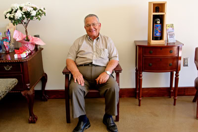 Smiling man sitting in office with wine-related decor and flowers, representing Lodi Winegrape Commission.