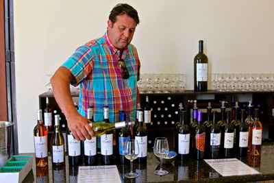 Man tasting wine at Lodi Winegrape Commission with bottles and glasses on the table.