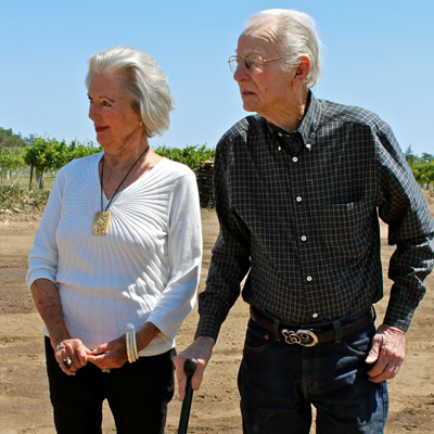 Elderly man and woman walking in a vineyard, enjoying the outdoors and wine country scenery.
