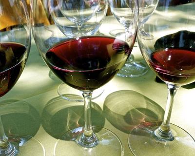 Glass of red wine from Lodi Winegrape Commission with multiple wine glasses in background.