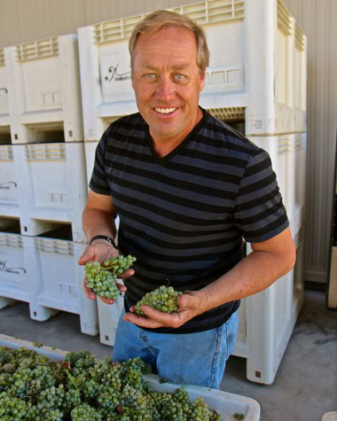 Man holding fresh grapes at Lodi Winegrape Commission, showcasing local wine grape harvest.