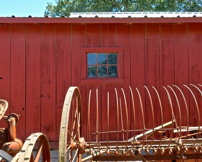 Rustic red barn with vintage farming tools and equipment for grape harvesting in Lodi, California.