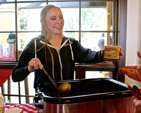 Woman serving food at a Lodi Winegrape Commission event, smiling and enjoying the moment.