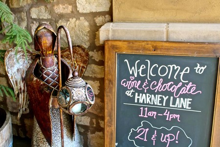 Chalkboard sign welcoming guests to wine and chocolate tasting at Harney Lane, 11am-4pm, for ages 21 and up.