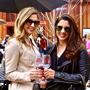 Two women enjoying wine at a Lodi Winegrape Commission event, smiling and holding glasses of red wine outdoors.