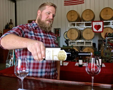 Man pouring wine into glasses at Lodi Winegrape Commission tasting event.