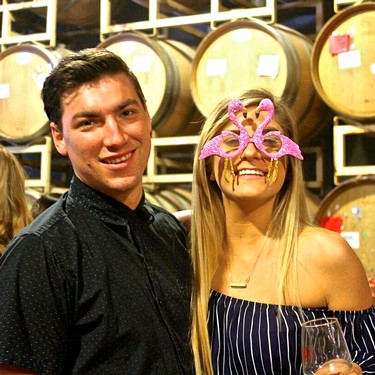 Two people celebrating at a Lodi Winegrape Commission event, one wearing a pink flamingo mask.