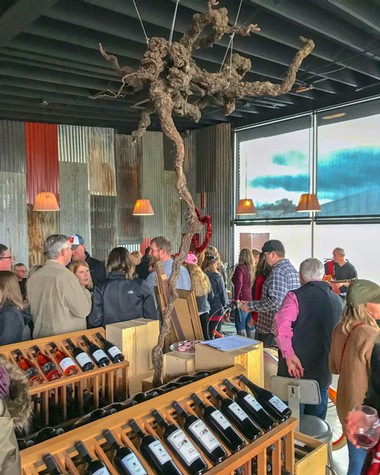 Crowd at Lodi Winegrape Commission tasting event with wine bottles and modern decor.