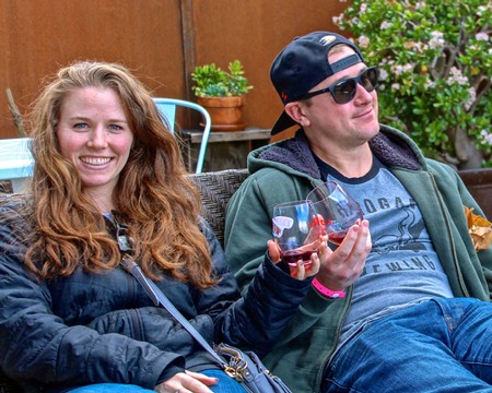 Two people enjoying wine outdoors, smiling and relaxing in a garden setting.